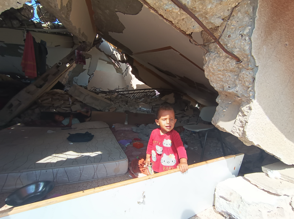 طفل يعيش مع أسرته تحت أنقاض منزله في بني سهيلا شرق خان يونس (أحلام حماد/ الترا فلسطين) 
