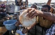 نازحون يحاولون الحصول على حصّة من الطعام في خانيونس جنوب قطاع غزة (Abed Rahim Khatib/ Getty)