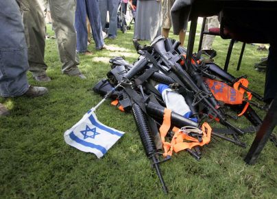 إسرائيليون يقفون بجوار كومة من الأسلحة التي سلمها المستوطنون المقيمون في مستوطنة جاني تال جنوب قطاع غزة في 8 أغسطس 2005