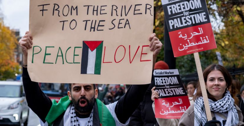 صورة أرشيفية لمتظاهر يحمل لافتة لعبارة "من النهر إلى البحر" 