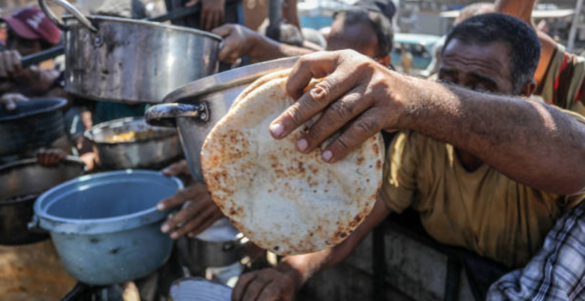 نازحون يحاولون الحصول على حصّة من الطعام في خانيونس جنوب قطاع غزة (Abed Rahim Khatib/ Getty)